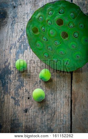 Three lotus seeds and calyx on wooden background
