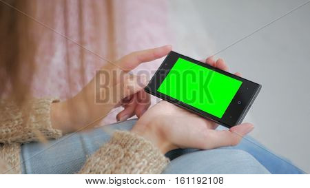 Woman looking at smartphone with green screen. Close up shot of woman's hands with mobile