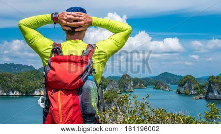 Traveler with Backpack enjoy the View over Roks in Kabui Bay near Waigeo. West Papuan, Raja Ampat. Indonesia