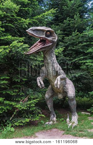 Landgraaf Netherlands - July 12 2016: Dinosaur Sculpture on a background of a coniferous tree in the park