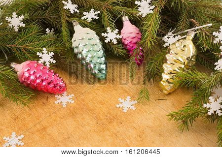 The branches of Christmas trees and fallal cone decorations on the background of wooden boards and snowflakes. Christmas and New Year's background.