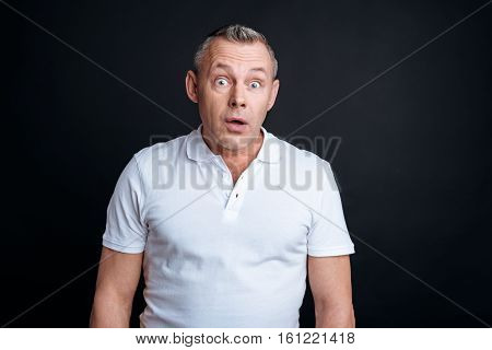 Overwhelmed with emotions. Pleasant handsome emotional man standing on the background and looking at you