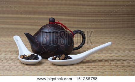 Black tea in a white ceramic spoon on the bamboo mat