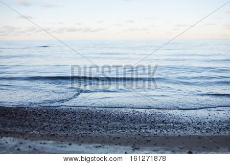 Abstract background of a pastel sunset on a peaceful sea with calm waves wafting to the shore