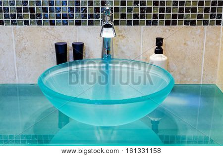 A washbasin made of tempered glass on wooden table white brick wall background