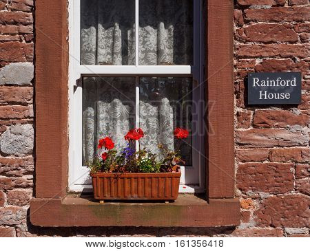 Colorful Cumbrian house detail featuring a window box with geraniums at Allonby Cumbria England.