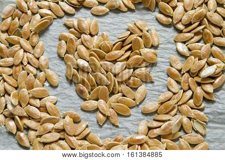 Heart of crude pumpkin seeds on the background