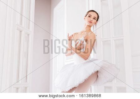 Follow your dreams. Graceful young brunette crossing both arms on the chest looking sideways while standing in the doorway
