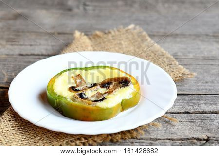 Homemade stuffed omelet on a plate and on old wooden table. Delicious omelet with fried mushrooms in a bell pepper. Healthy egg recipe for breakfast. Closeup