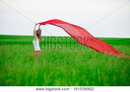 Young lady runing with tissue in green field. Beautiful happy woman walking  in the summer rural meadow. Outdoor summer portrait of pretty sport style woman jumping with fabric. Beautiful fit tan girl. Sexy slim model caucasian ethnicity outdoors.