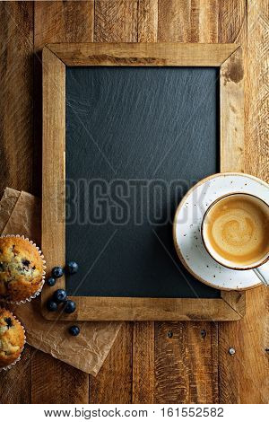 Freshly baked blueberry muffins on chalkboard with milk and coffee on the table overhead shot with copyspace