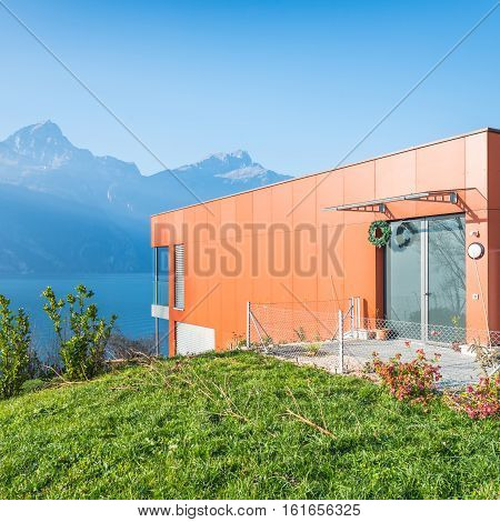 Fluelen Switzerland - 4. December 2016. Villa on the lake in the Swiss Alps. House a modern red. High windows with floor to ceiling and glass doors.