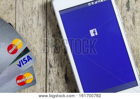BUNGKAN THAILAND - NOVEMBER 10 2015: smart phone with Facebook on screen and credit card on wood background