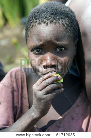 AFRICA, TANZANIA, MAY, 10, 2016 - Close-up portrait  cute african girl of the hadza tribe, that eats fruit in Tanzania, Africa
