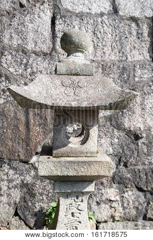 Stone lantern in front of a stone brick wall