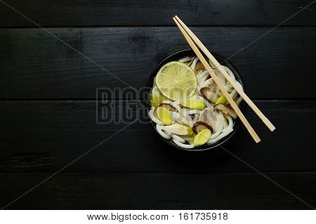 Japanese soup with udon noodles mushrooms leeks and lime. Concept of eating. Concept of asian food. Concept of japanese food. Top down. Flat lay. Selective focus.