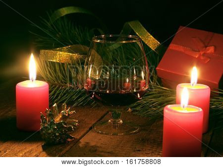 Brandy glass and candles on black background.