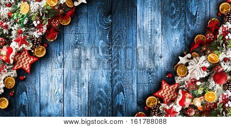 Merry Christmas Frame with green pine, colorful baubles, knots with berries,stars, orangesand other seasonal stuff over an old wooden aged background
