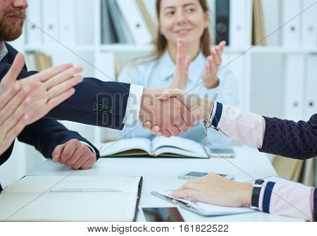 Male and female handshake in office. Serious business and partnership concept. Partners made deal sealed with handclasp.