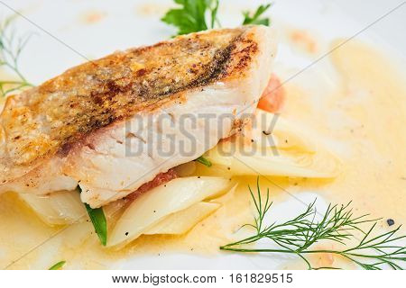 Pike perch fillet with leeks and beurre Blanc served in a white plate