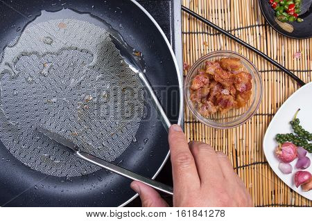 Chef holding crispy bacon to cup by tongs / cooking spicy spaghetti concept