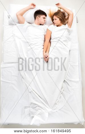The young lovely couple lying in a white bed, love lconcept, top view
