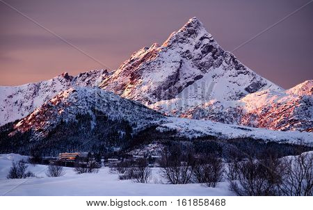 Skottinden snowy mountain in red morning light Lofoten