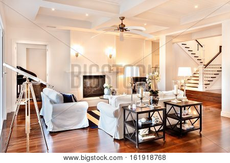 Beautiful drawing room with glossy wooden floor and telescope at the window and white sofa