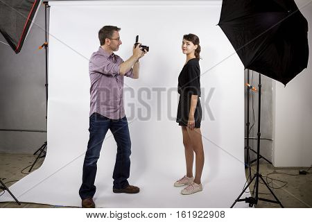 Photographer in a studio demonstrating how to light a model and take photos. He is using softboxes with a white background.