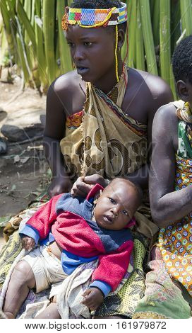 AFRICA, TANZANIA, MAY, 10, 2016 - Portrait woman in bead decoration with a baby of the Hadzabe tribe. Hadzabe tribe threatened by extinction in Tanzania, Africa