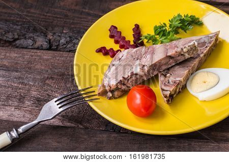Headcheese on a yellow plate. Wooden background. Top view. Close-up