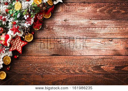 Merry Christmas Frame with green pine, colorful baubles, knots with berries,stars, orangesand other seasonal stuff over an old wooden aged background