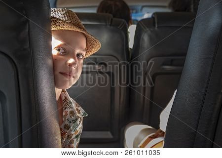Boy Looks Out From Behind Chair In Cabin Bus. Portrait Of A Smiling Child (8-10 Years) In The Light 
