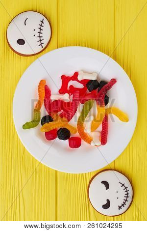 Halloween Background With Cookies And Candies. Top View On Plate With Colorful Jelly Sweets For Hall