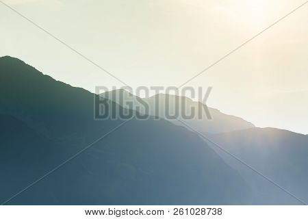A Dreamy, Hazy Landscape Of A Mountains Close To Sunset. Sun Flase And Misty Look In Blue Tones. Mo