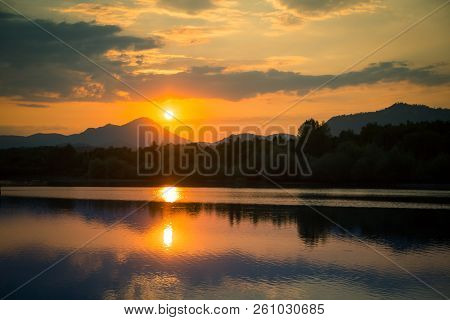 A Beautiful, Colorful Sunset Landscape With Lake, Mountain And Forest. Natural Evening Scenery Over 