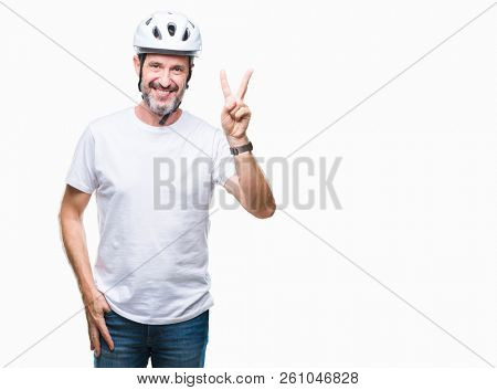 Middle age senior hoary cyclist man wearing bike safety helment isolated background smiling with happy face winking at the camera doing victory sign. Number two.