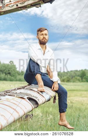 A Man In A Shirt Sitting On The Wing Of An Old Plane