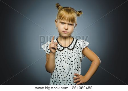 Displeased And Contemptuous Girl With Threatens Finger On Gray Background
