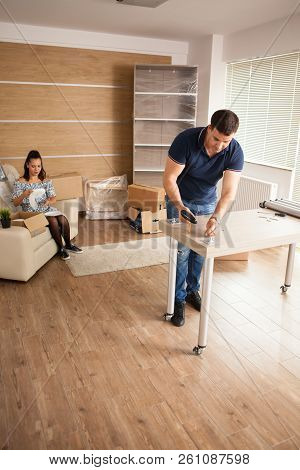 Man Is Working With Furniture Assembly Using Electric Screwdriver In New House.