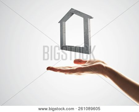 Close Up Of Hand Presenting Stone House Symbol In Palm. Mixed Media