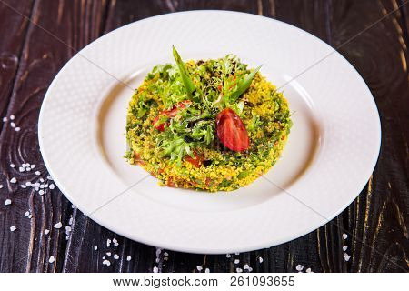 Salad From Bulgur And Fresh Vegetabes On White Plate In Restaurant