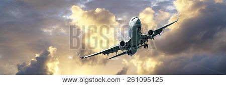 A Passenger Jet Airliner Flying Overhead Closeup With A Golden Yellow Coloured Cumulus Cloud Formati