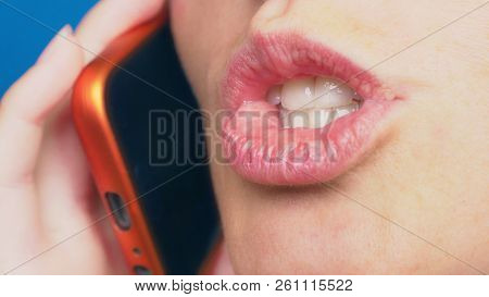 Close-up, Female Lips Without Makeup Talking On A Red Mobile Phone, Against A Blue Background.