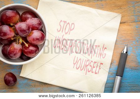 Stop underestimating yourself - inspirational handwriting on a napkin with fresh grapes