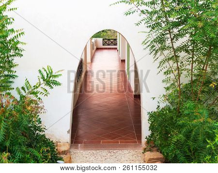 Arched Entrance With Some Greenery. Archway To The Rooms At The Resort