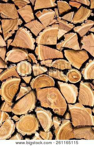 Vertical Photo Of A Dry Chopped Wood, Wooden Logs For A Fire Or A Fireplace Neatly Stacked In A Pile