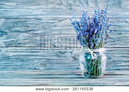 A Photo Of A Bouquet Of Lavender In A Glass Vase With A Neck Bandaged With A Rough Rope On The Right