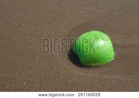 Green Apple In The Sand On The Beach