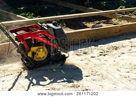 Builder With Vibratory Plates Seals The Base Sand For Pouring Concrete.